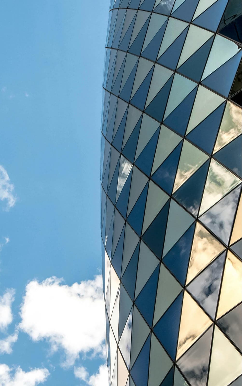 Glass office tower facade against a blue sky