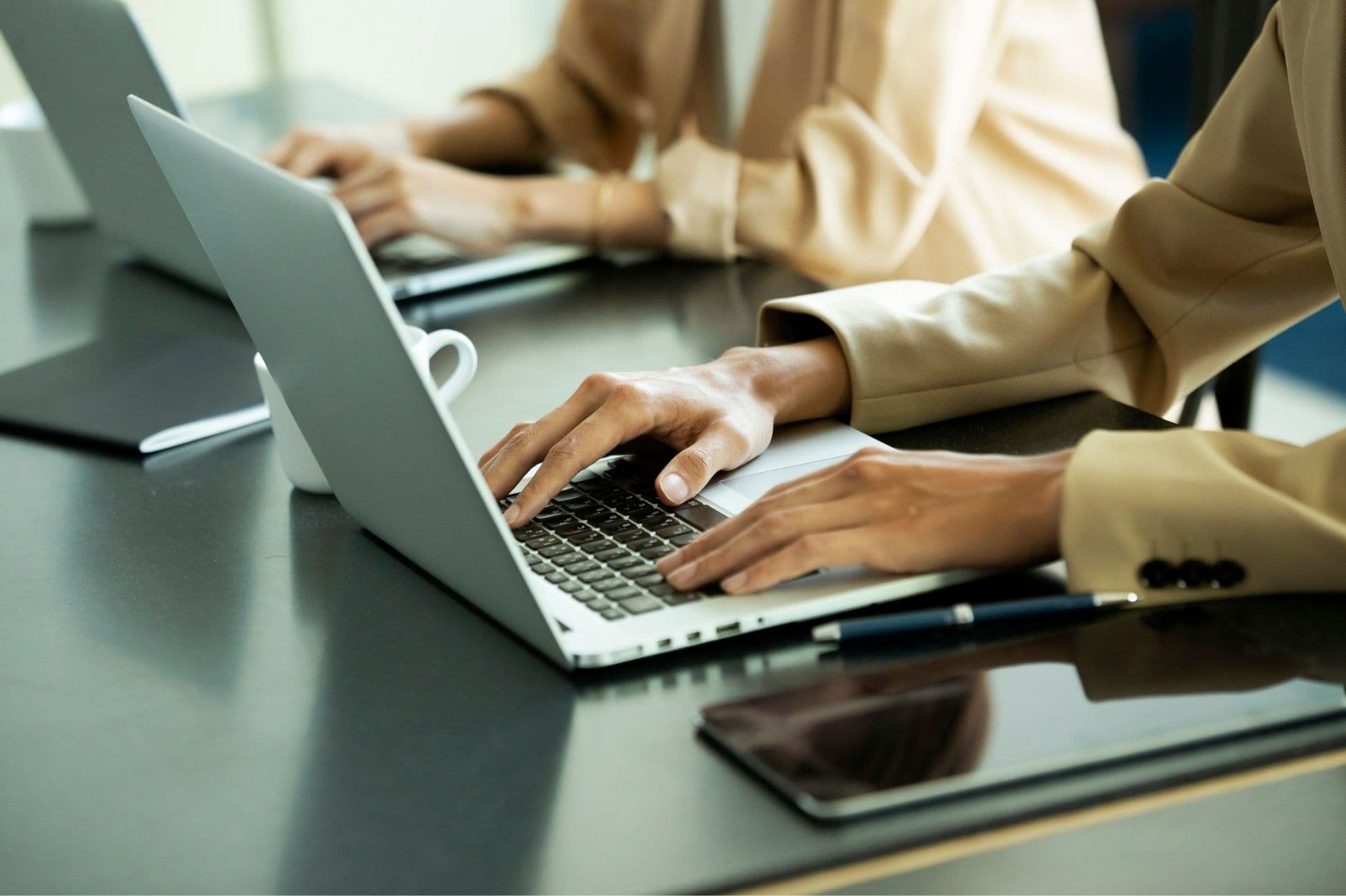 Close-up of hands typing on a laptop at a dark desk